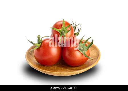 Cumulo di pomodori ciliegini maturi in piastra di legno su sfondo bianco. I pomodori o Solanum lycopersicum o lycopersicon esculentum sono fonte dell'antiox Foto Stock