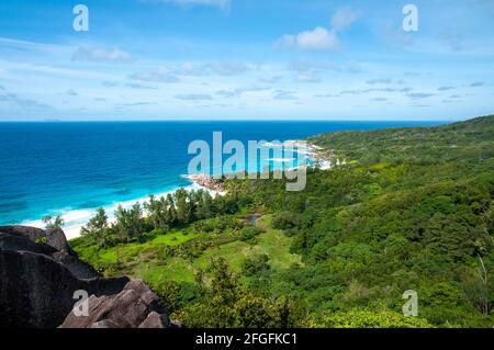 Una vista incantevole dell'oceano e dell'isola verde luccicante sotto il cielo blu nuvoloso sulla costa Foto Stock