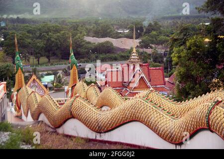 Vista laterale della grande scultura di naga in oro e bronzo lungo la scala fino alla statua del Buddha nel tempio tailandese. Foto Stock