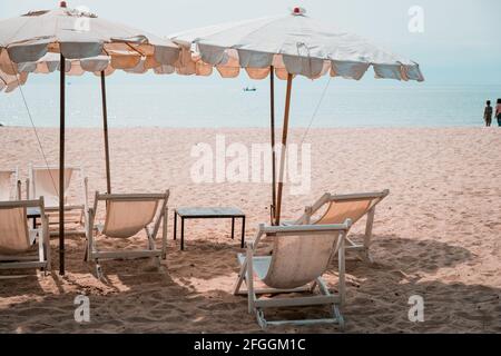 Sdraio e Parasol bianco nella spiaggia tropicale. Ombrellone bianco sulla spiaggia in estate Foto Stock