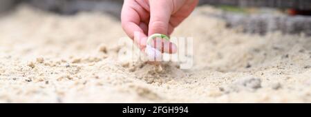 una mano dei bambini che piantano un seme germogliato di aglio in un letto da giardino con sabbia in primavera. banner Foto Stock