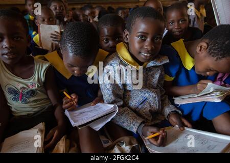 Mzuzu, Malawi. 30-05-2018. Una ragazza nera sta guardando la macchina fotografica mentre scrive nel suo notebook come il resto dei suoi compagni di scuola in una zona rurale di Mala Foto Stock