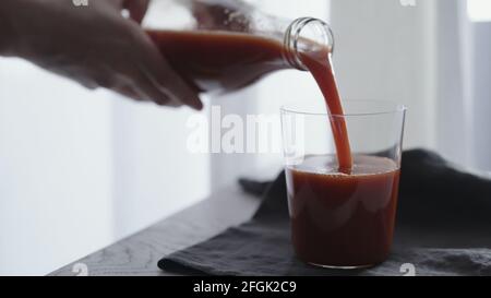 l'uomo versa il succo di pomodoro in un bicchiere da bicchiere su un panno di lino, foto ampia Foto Stock