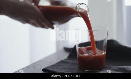 l'uomo versa il succo di pomodoro in un bicchiere da bicchiere su un panno di lino, foto ampia Foto Stock