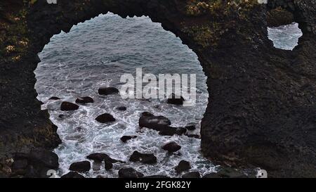 Closeup vista di buchi in arco naturale Gatklettur formato da rocce vulcaniche di basalto sulla costa atlantica ruvida di Arnarstapi, Snæfellsnes, Islanda. Foto Stock
