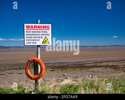 Sulla costa nord-occidentale di Cumbria Solway, un cartello avverte di maree pericolose, sabbia affondante e fango alle basse maree. Foto Stock