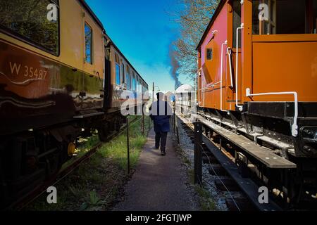 Una guardia del treno passa accanto alle carrozze alla stazione di Cranmore, Somerset, sulla East Somerset Railway, durante il loro primo fine settimana di gala a vapore come il blocco facilita. Data immagine: Domenica 25 aprile 2021. Foto Stock