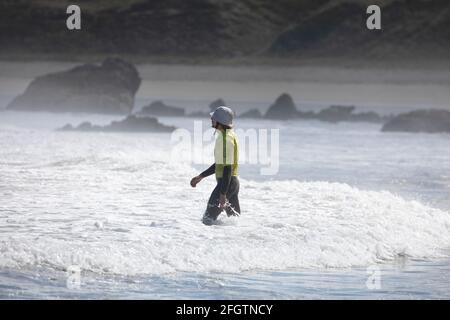 Galizia, Spagna - 2 agosto 2020: Uno degli istruttori di surf entra in acqua, protetta da una muta, per iniziare le lezioni di surf sulla spiaggia di San Foto Stock