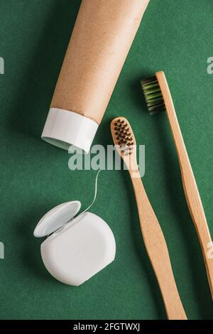 Filo interdentale, dentifricio e spazzolini da denti di bambù su verde Foto Stock