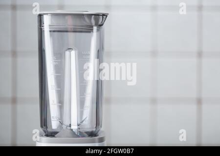 Svuotare il frullatore elettrico in cucina per cocktail e cibi sani. Frullatore bianco sul tavolo con piastrelle da cucina leggere. Concetto minimo, spazio di copia Foto Stock