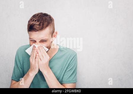 Il giovane sta soffiando fuori un tovagliolo di carta. Concetto di freddo Foto Stock