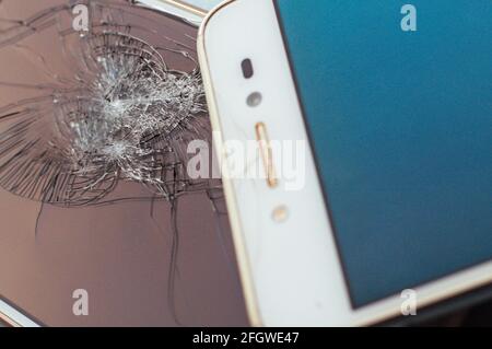 Due telefoni cellulari primi piano con schermi rotti. Foto Stock