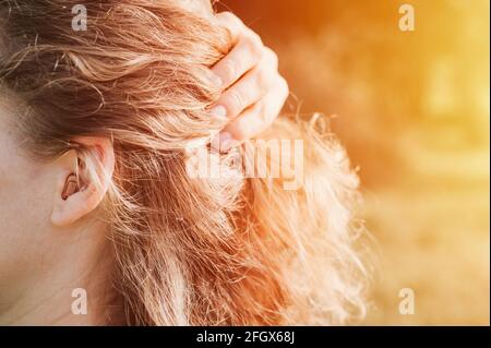 piccolo apparecchio acustico intra-canale nell'orecchio di una donna Foto Stock