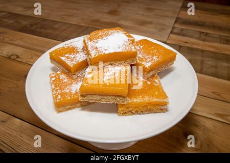 Un mucchio di deliziose piazze di limone, dolci fatti in casa su un tavolo da cucina in legno Foto Stock