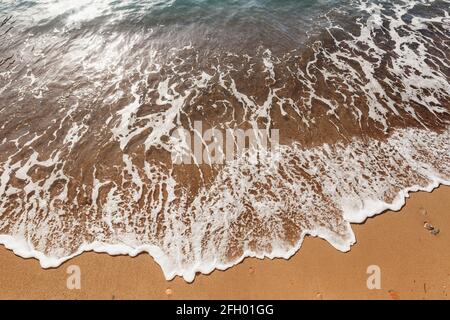 Surf in mare. L'onda scorre sulla spiaggia Foto Stock