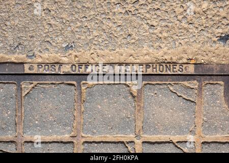 Copertura di ispezione dei telefoni postali in ghisa e calcestruzzo montato sul fondo stradale Foto Stock