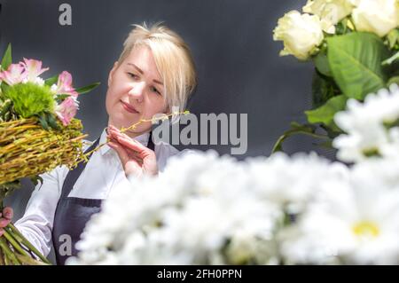 Fiorista giovane donna tra mazzi di fiori in un negozio di fiori da vicino. Foto Stock