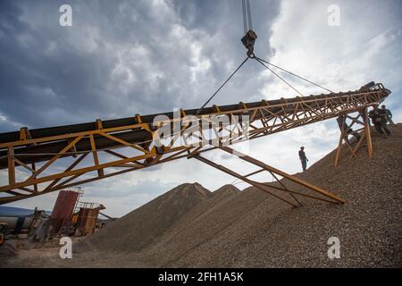 Addetti all'assemblaggio di macchine per frantumazione rocce. Utilizzare per la distruzione del minerale d'oro. Trave di sollevamento in metallo. Stabilimento minerario e di trasformazione Altynalmas. Foto Stock