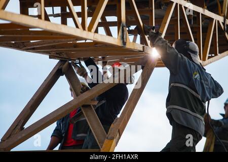 Addetto e saldatore che assemblano la macchina frantumatrice. Utilizzare per la distruzione del minerale d'oro. Stabilimento minerario e di trasformazione Altynalmas. Regione di Almaty, Kazakistan Foto Stock