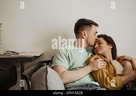 Bella giovane coppia che mostra una sensazione romantica l'una all'altra seduta sul divano. Buona famiglia che si trasferiscono in un nuovo appartamento Foto Stock