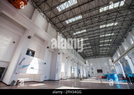 Interno della centrale idroelettrica Moinak. Giù generatori elettrici blu di destra e gruppo di gente. Foto Stock
