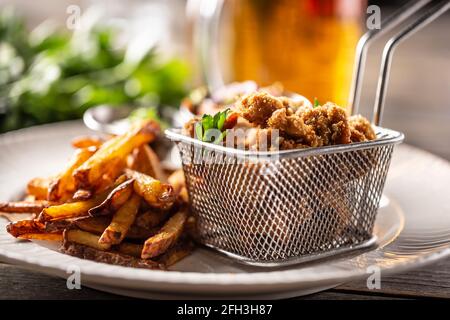 Pepite di pollo fritte con patatine servite su un piatto. Foto Stock