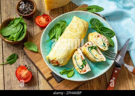 Cucina giapponese. Piatto nazionale giapponese Omelet tamago yaki per colazione. Uovo arrotolato con spinaci, pomodoro e formaggio su un tavolo di legno. Foto Stock