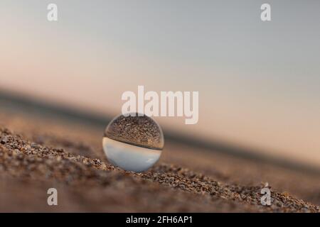 sfera ottica di vetro sulla costa azzurra sabbiosa del mare Foto Stock