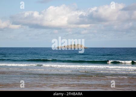 Surfista sulla spiaggia di Somo con Isola di Mouro e Faro in background; Santander; Cantabria; Spagna Foto Stock