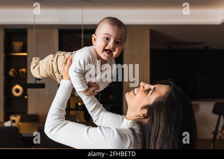 Allegra femmina etnica con vitiligo condizione della pelle e cellulare che cammina sul lungomare mentre si guarda schermo contro l'oceano sotto il cielo blu Foto Stock