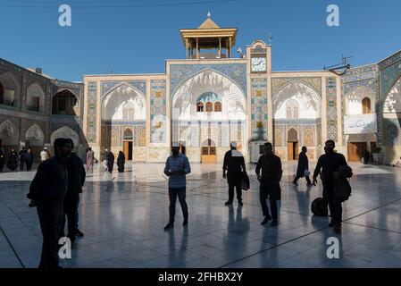 Qom, Iran: Pellegrini all'ombra in un cortile con le pareti laterali del santo Santuario di Fatima Masumeh . Foto Stock