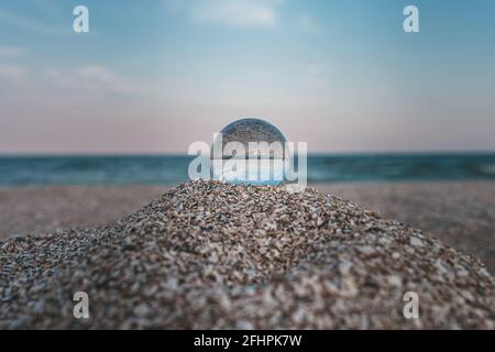 sfera ottica di vetro sulla costa azzurra sabbiosa del mare Foto Stock