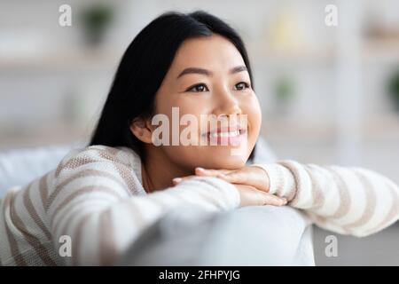 Primo piano Ritratto di Dreamy Happy Young Asian Woman rilassante a. Casa Foto Stock