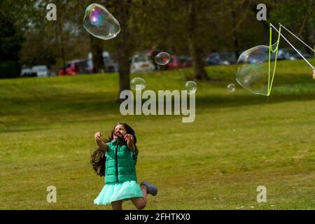 Harrogate Park, dove una giovane ragazza sta inseguendo le bolle saponate create con una Bubble Wand, North Yorkshire, Inghilterra, Regno Unito. Foto Stock