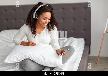 Soddisfatta giovane donna nera che ascolta la musica Foto Stock