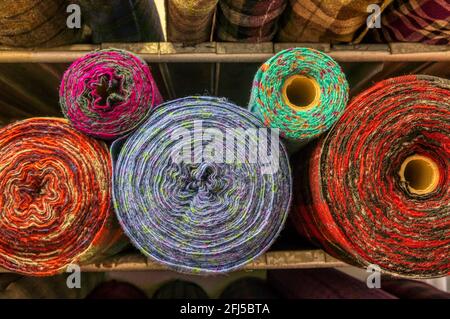 Rotoli colorati di Harris tinto tweed su scaffali di magazzino. Foto Stock