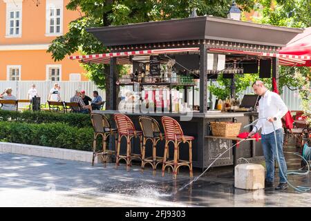 Budapest, Ungheria - 10 agosto 2019: Chiosco caffè locale / bar, lavoratori di lavaggio strada marciapiede Foto Stock