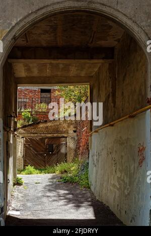 Passaggio ad arco in un vecchio cortile con garage e una casa in mattoni nella città di Vyborg, in una giornata estiva soleggiata. Foto Stock