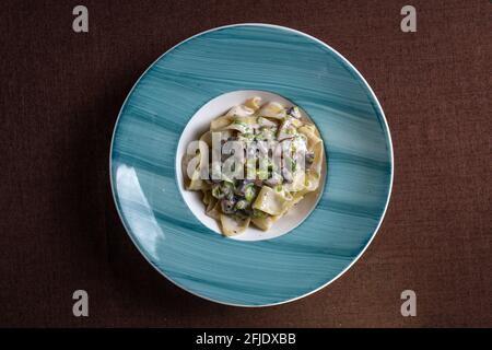 pasta con salsa di funghi su un piatto blu vista dall'alto. Foto Stock
