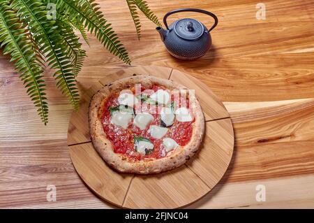 pizza italiana margarita con basilico e mozzarella su legno stand Foto Stock