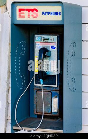 Un telefono pubblico a gettoni, chiamato anche telefono a pagamento, è appeso al muro al di fuori del deposito ferroviario di Pascagoula a Pascagoula, Mississippi. Foto Stock