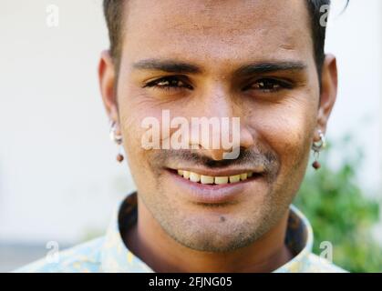 Un ritratto di un giovane maschio indiano sorridente in piedi all'aperto Foto Stock