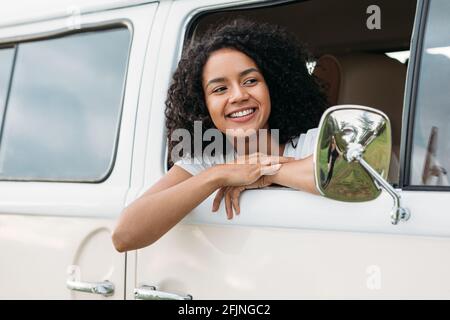 Giovane donna di razza mista che guarda fuori dalla macchina e. sorridente Foto Stock