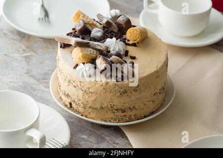 La tavola è impostata per il tè: tisane e piattini e un pan di Spagna con panna al piano di pietra. Primo piano della torta Foto Stock