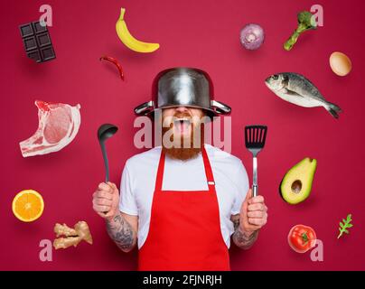 Uomo chef è pronto a combattere in cucina. Burgundies sfondo Foto Stock