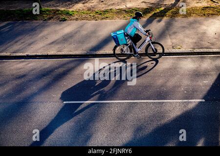 Un ciclista getta una lunga ombra nel tardo pomeriggio sole Foto Stock