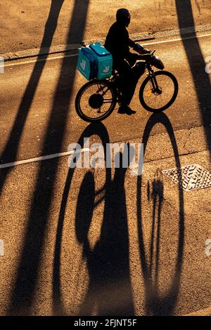 Un ciclista getta una lunga ombra nel tardo pomeriggio sole Foto Stock