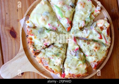 Una deliziosa pizza italiana servita sul piatto di legno Foto Stock