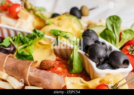Primo piano su cibo antipasto sulla tavola olive nere basilico e carne stagionata Foto Stock