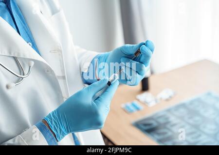 Closeup medico mano in guanti medici riempire siringa con farmaco dose dal flaconcino Foto Stock